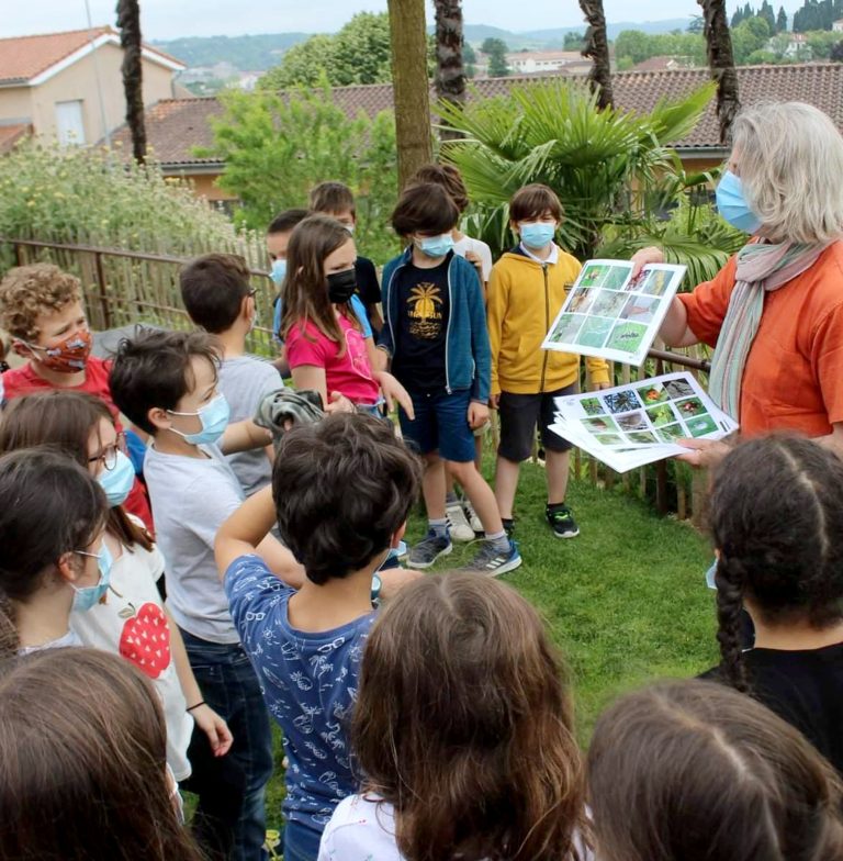 Image d’ enfants de 7-8 ans autour de Mme Muhlberger edith qui leur montrent des planches de reconnaissance des insectes lors d’une journée de formation la ville d’Auch